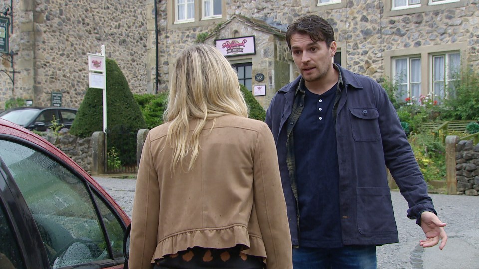 a man and a woman are standing in front of a building with a sign that says ' shepherd 's hut '