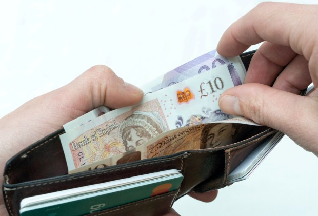 a person is holding a wallet full of bank of england money