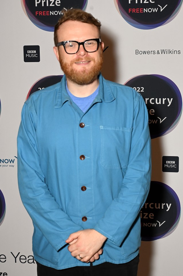 a man in a blue jacket stands in front of a wall that says prize freenow