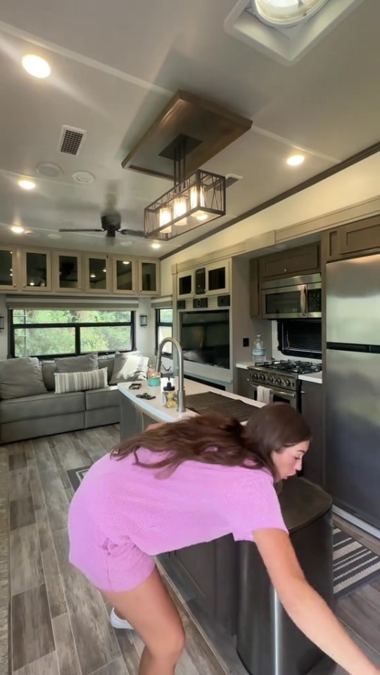 a woman in a purple shirt is bending over in a kitchen