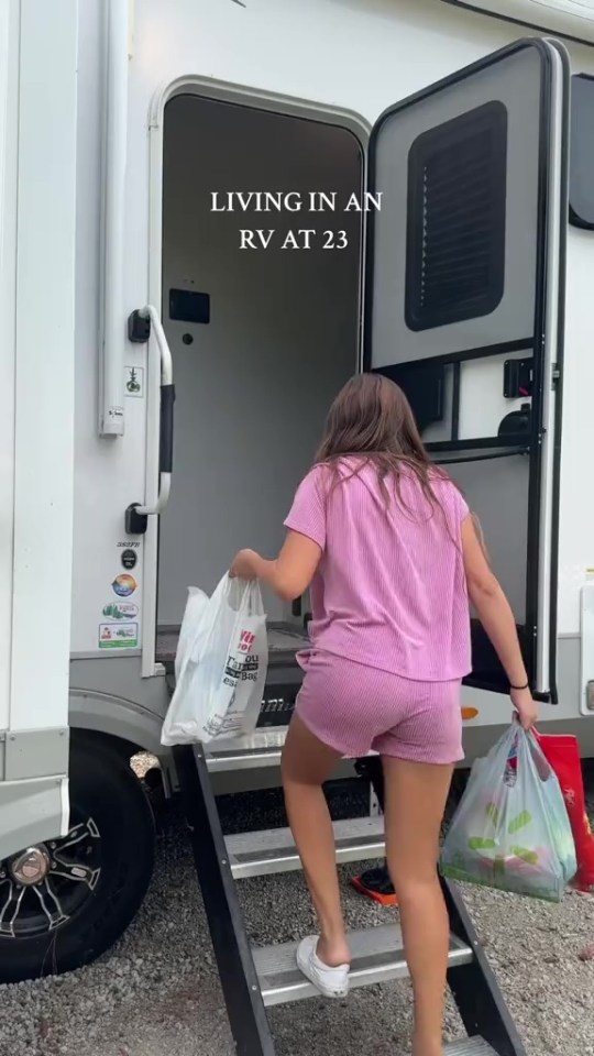 a woman in a pink shirt and shorts is getting out of a rv