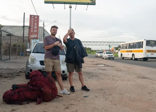 two men standing in front of a bus that says escolar