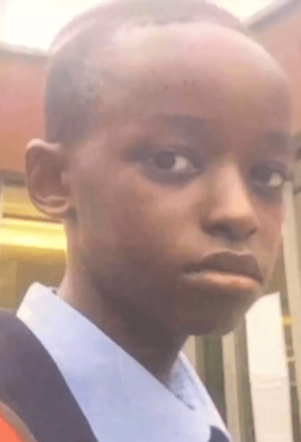 a young boy in a blue shirt and black tie is making a funny face .