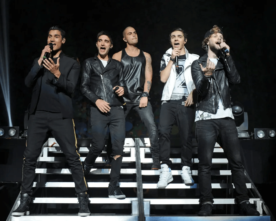 a group of men singing into microphones on a stage