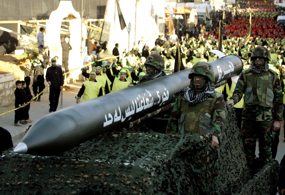 Hezbollah militants ride on a vehicle carrying a Fajr 5 missile during an annual parade