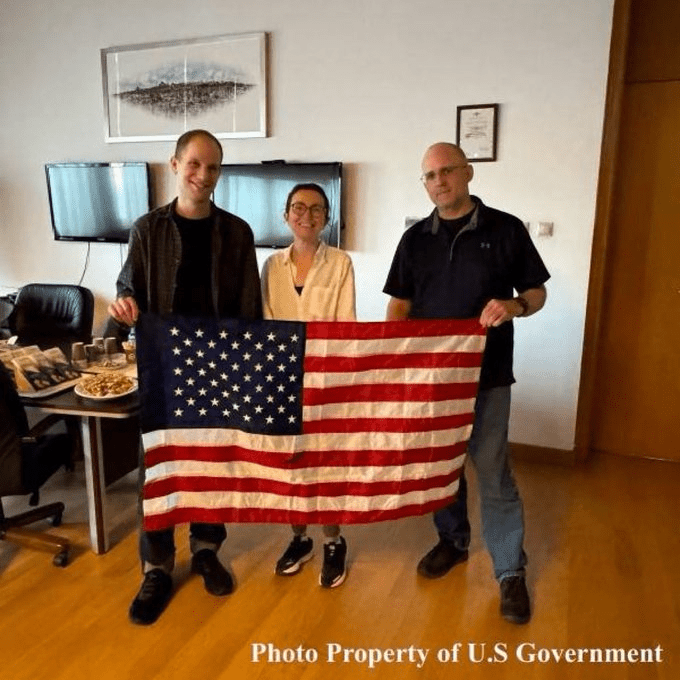 Wall Street Journal reporter Evan Gershkovich, Russian-American journalist Alsu Kurmasheva and former US marine Paul Whelan pose with a US flag