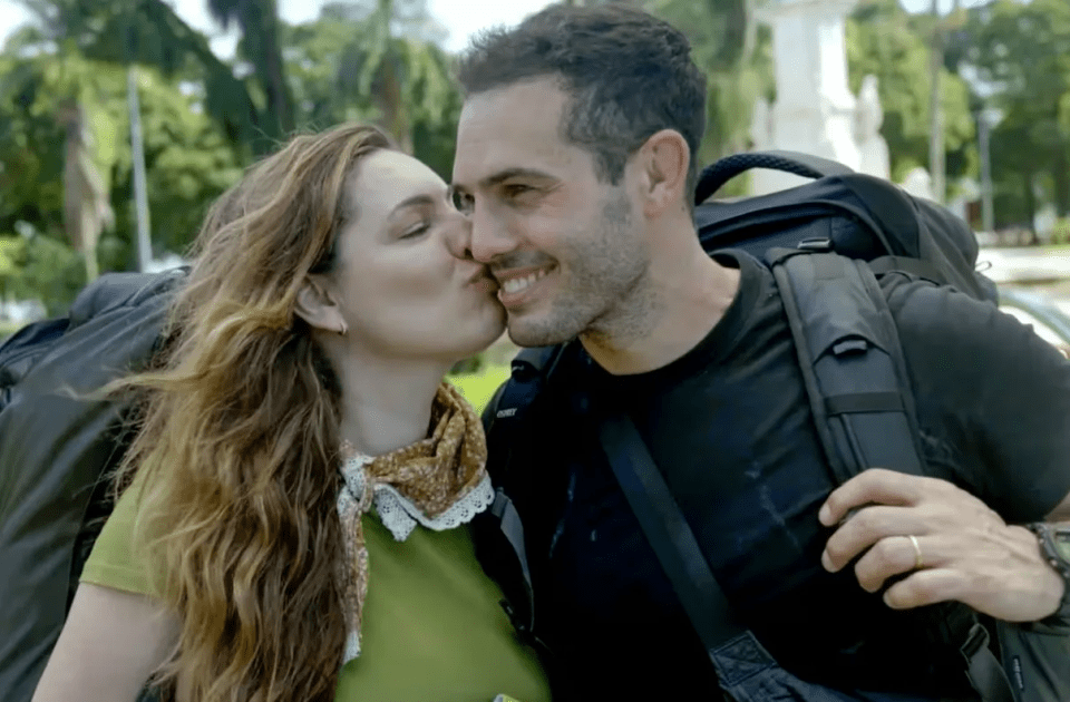 a woman kisses a man on the cheek in front of a statue