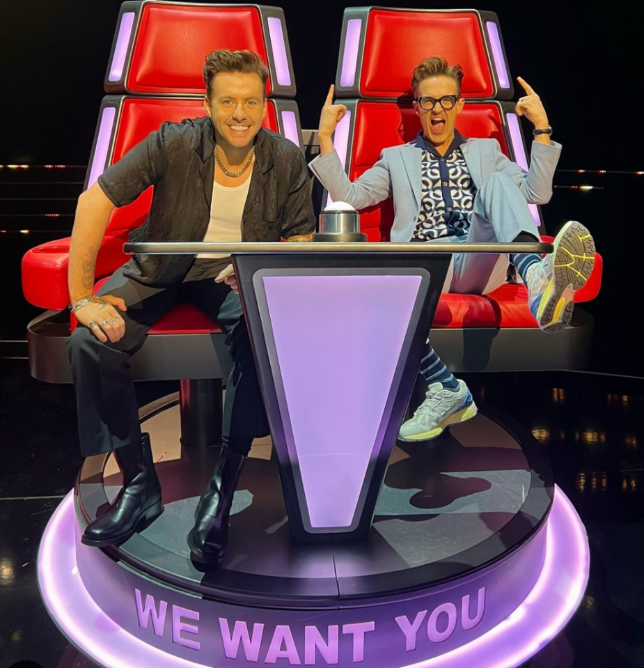 two men are sitting in front of a sign that says we want you