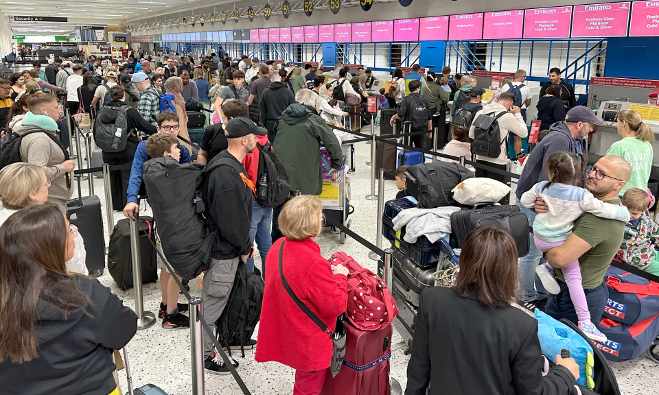 a crowd of people waiting at a check in counter for emirates