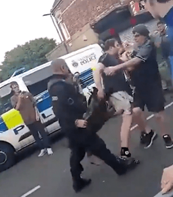 a group of people are standing on a street in front of a police van .