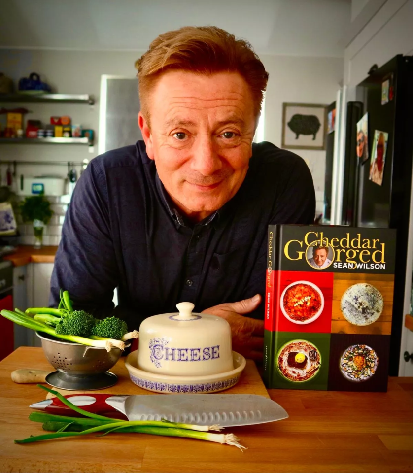 a man standing next to a book titled cheddar gorged