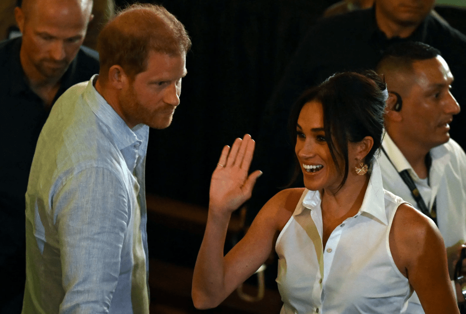 a woman in a white shirt waves to a man in a blue shirt