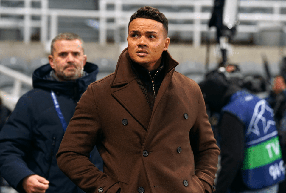 a man in a brown coat stands in a stadium