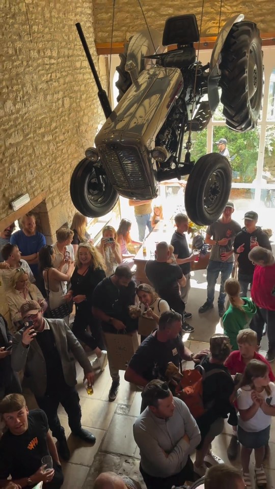 a group of people gathered around a tractor hanging from the ceiling