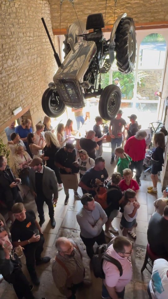 a group of people are gathered around a tractor hanging from the ceiling