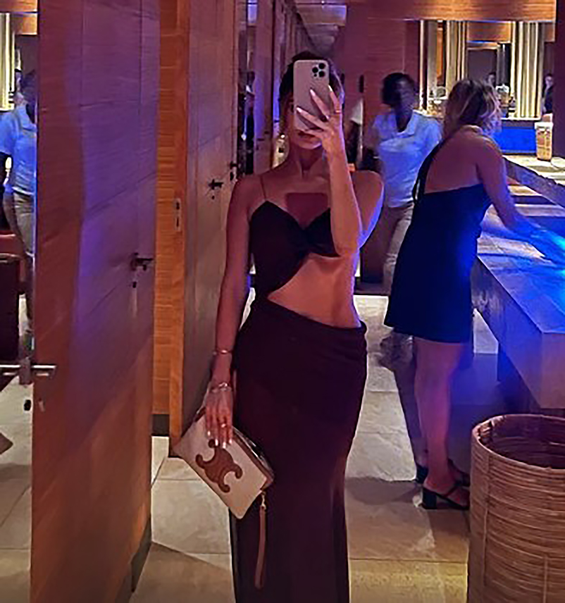 a woman in a black dress is taking a selfie in a mirror .