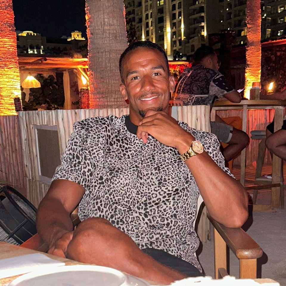 a man in a leopard print shirt sits at a table