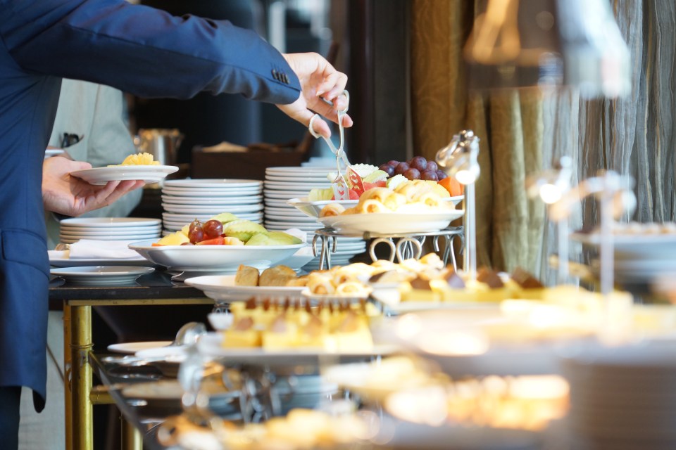 a man reaches for a plate of fruit at a buffet