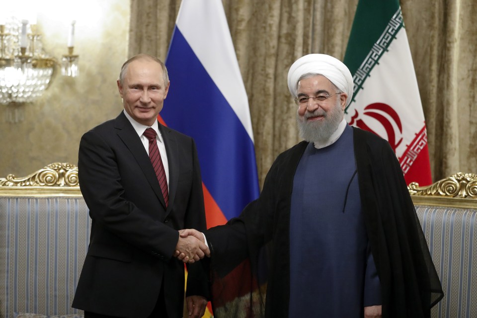 Russia’s President Vladimir Putin (L) and Iran’s former President Hassan Rouhani shake hands at Sa’dabad residence