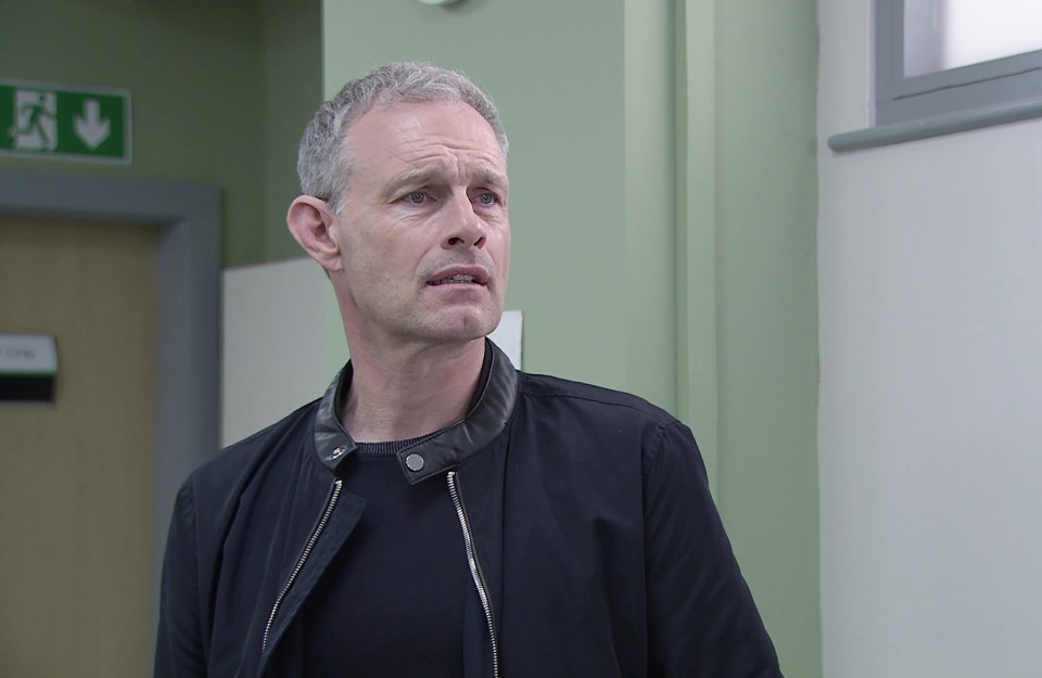 a man in a black jacket stands in front of a green exit sign