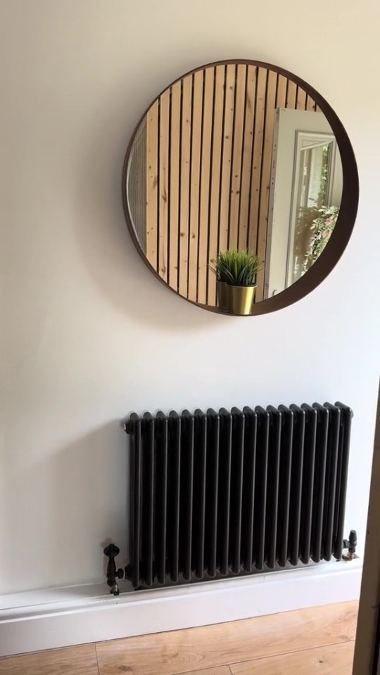 a round mirror hangs above a black radiator