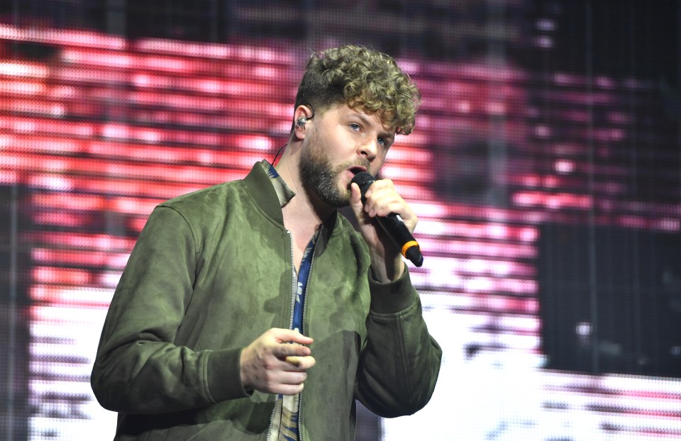 a man in a green jacket sings into a microphone