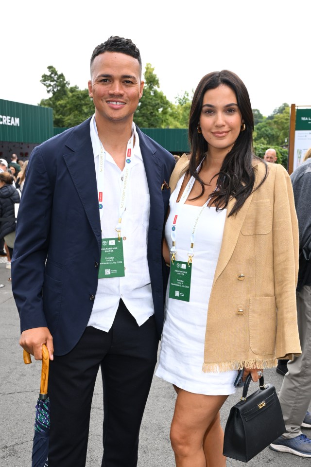 a man in a suit and a woman in a white dress pose for a picture