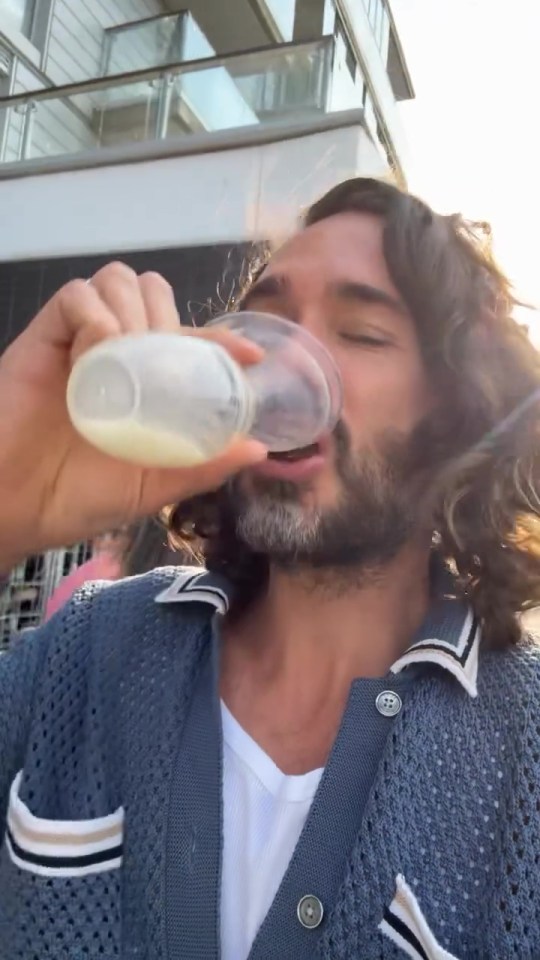 a man with long hair is drinking from a bottle