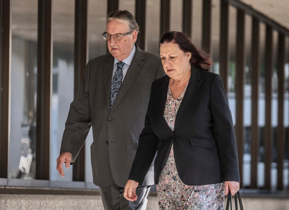 a man in a suit and tie walks next to a woman in a black jacket