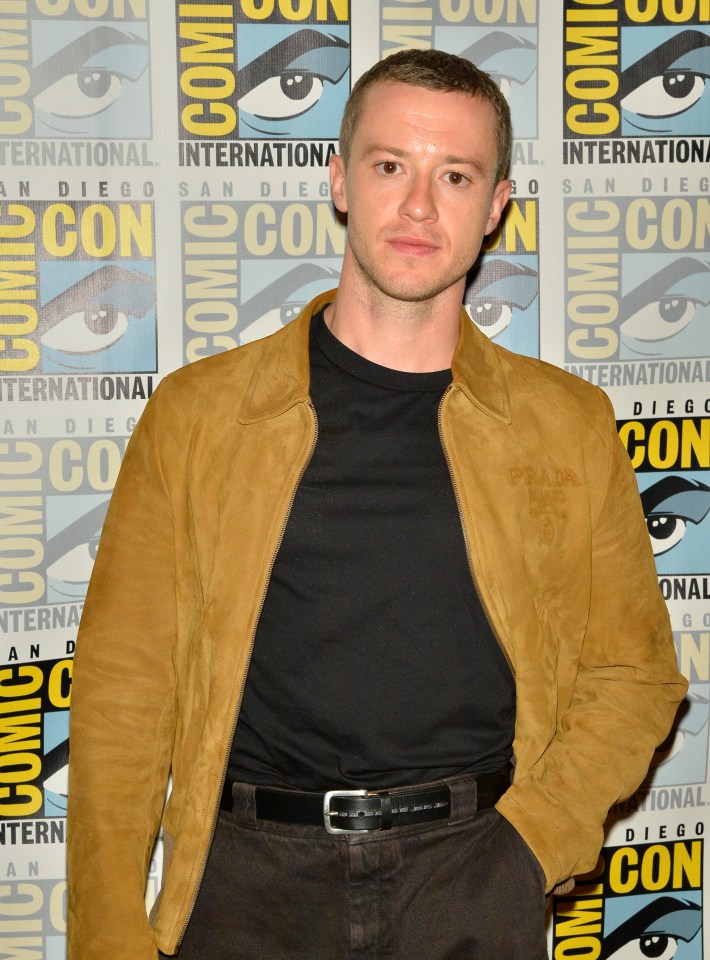 a man stands in front of a comic con sign