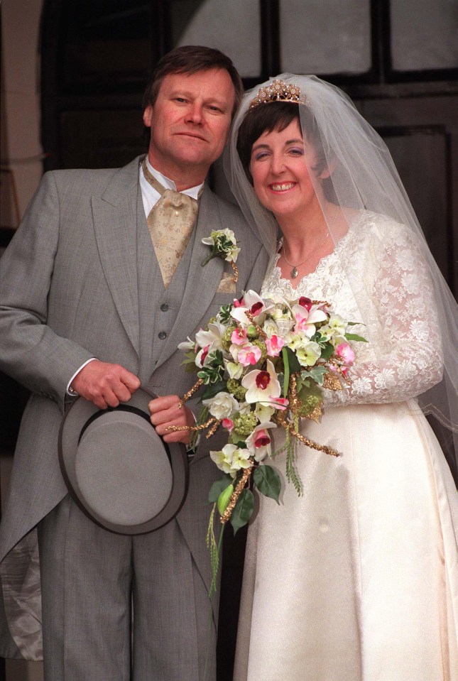 a bride and groom pose for a picture with the bride holding a bouquet of flowers