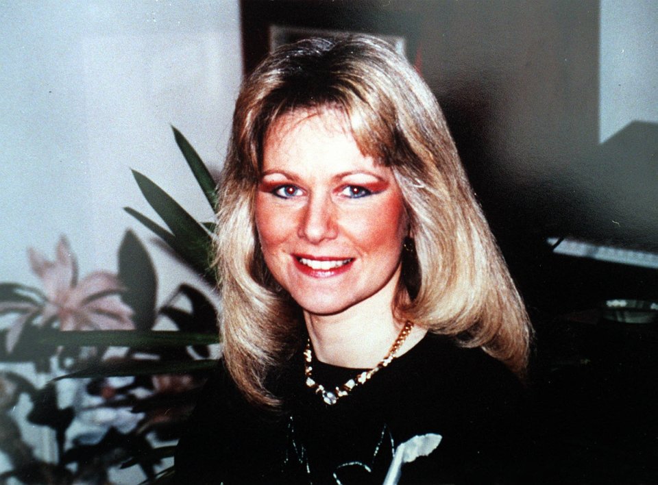 a woman with blonde hair and a necklace smiles for the camera