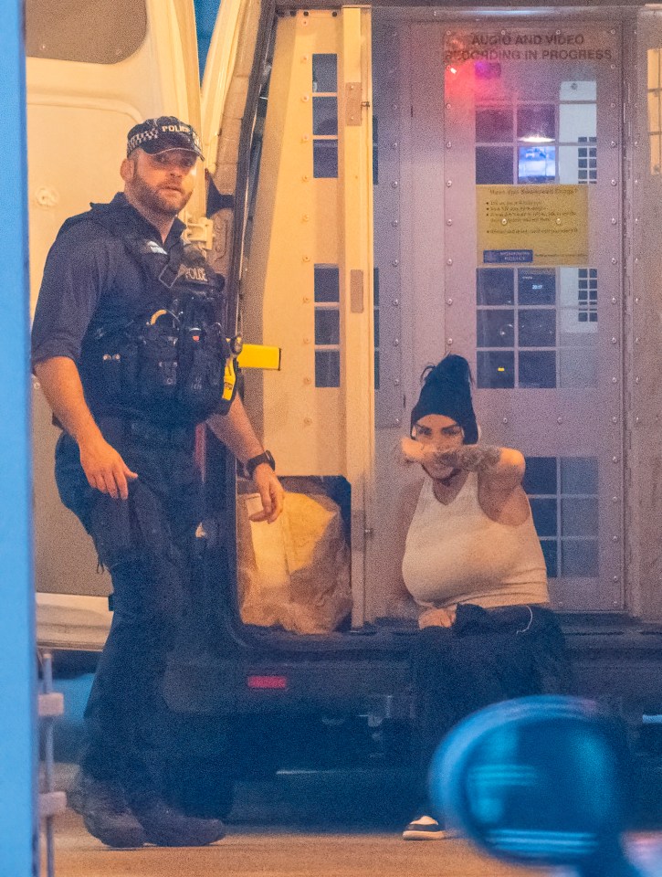 a man in a police uniform stands next to a woman in front of a door that says audio and video recording in progress