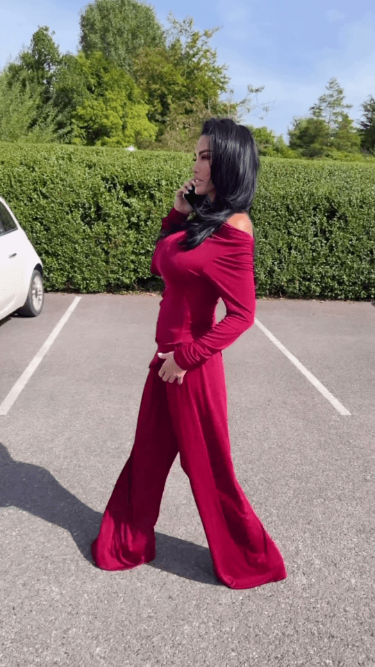 a woman in a red dress is standing in a parking lot