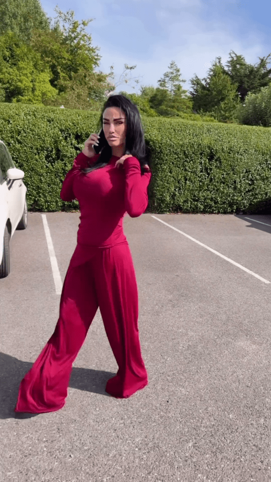 a woman in a red outfit is standing in a parking lot