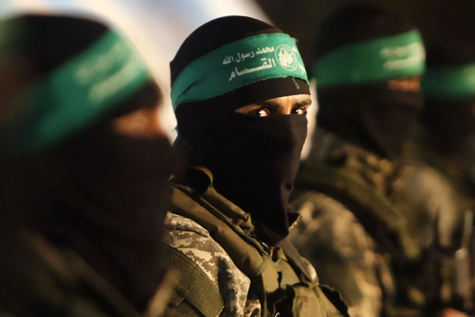 A Hamas terrorist, clad in military-style gear and a black mask with the logo-branded headband