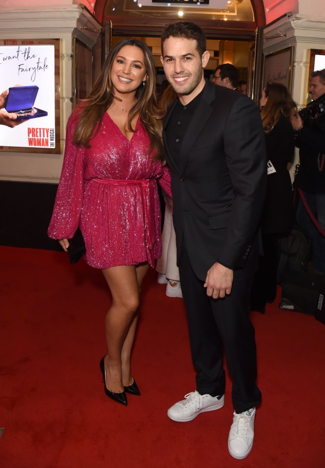 a woman in a pink dress stands next to a man on a red carpet