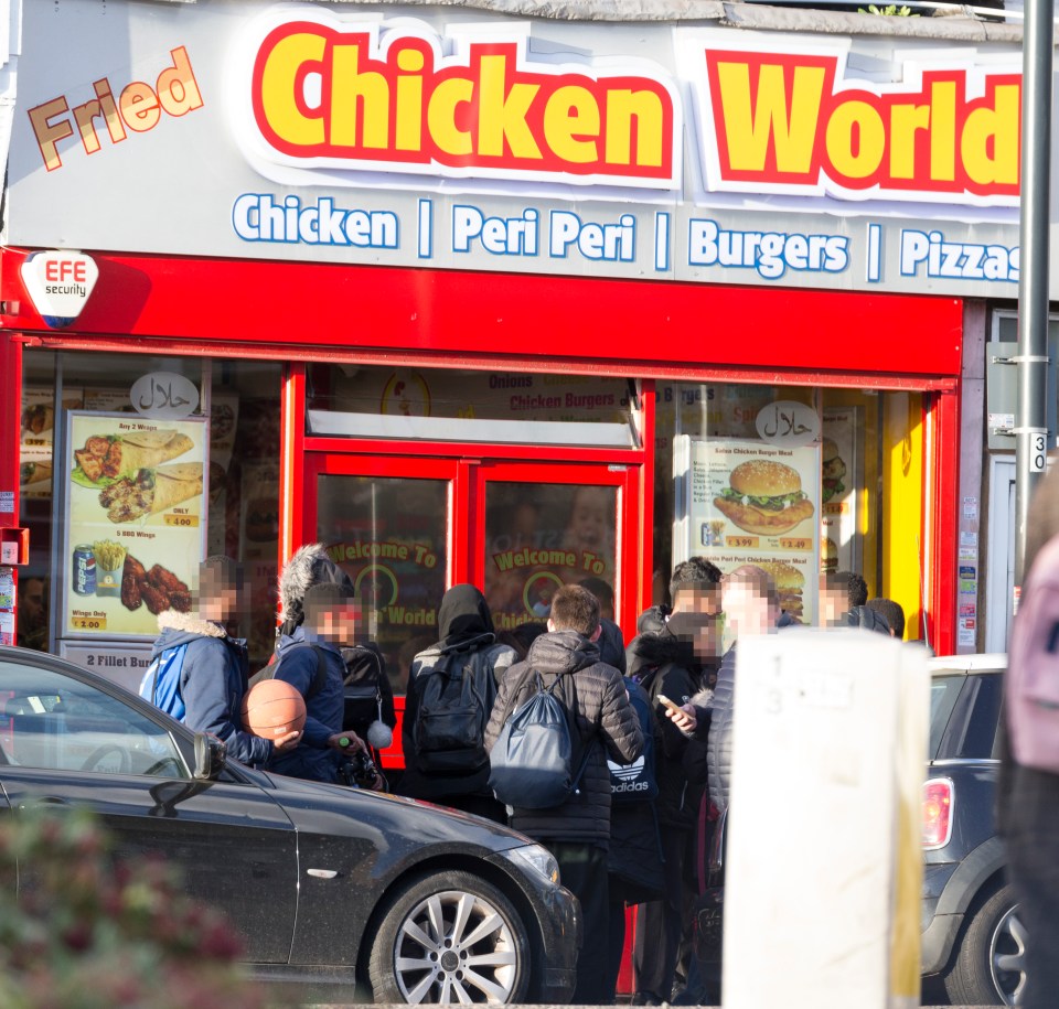 a group of people standing outside of a chicken world restaurant