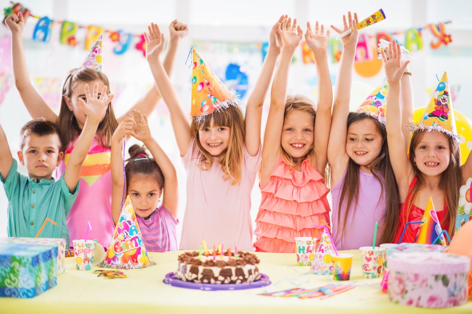 a group of children are celebrating a birthday with their arms in the air