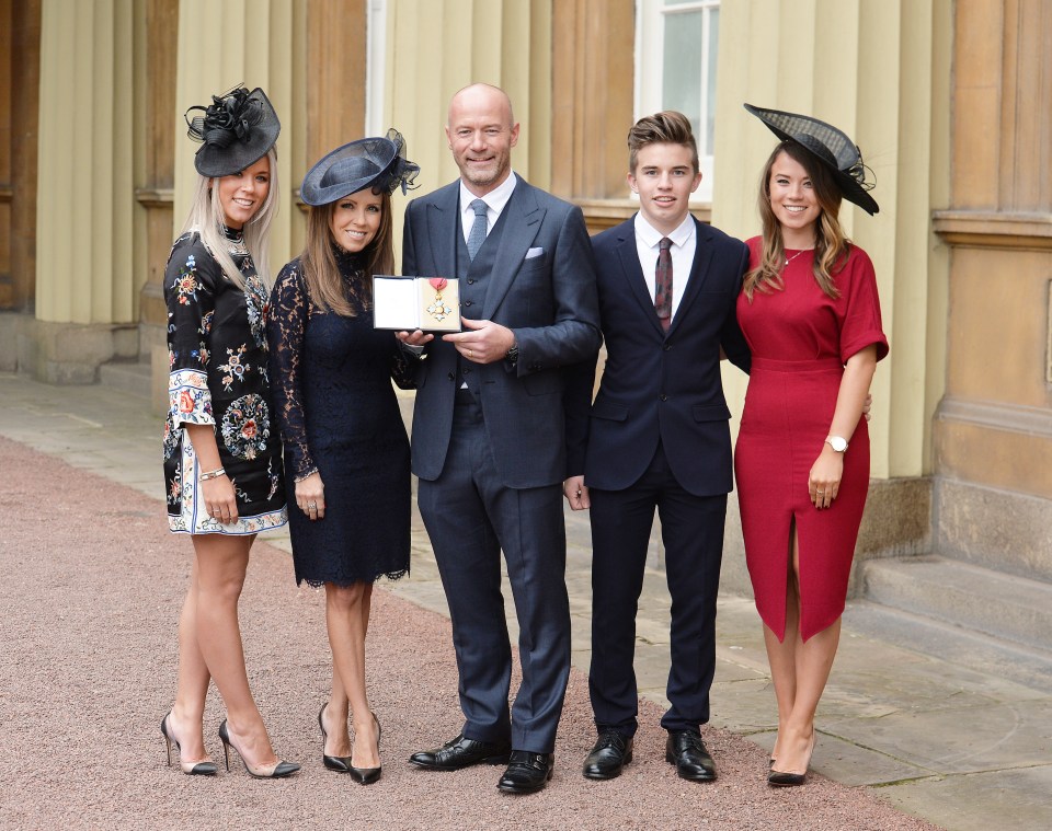 a man in a suit holds a medal in front of his family