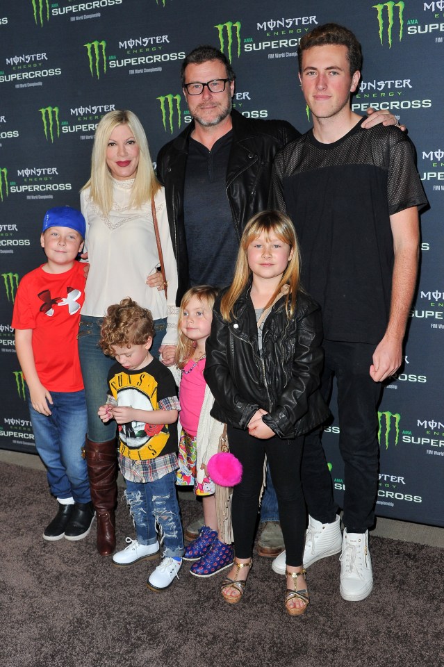 a family poses in front of a monster supercross poster