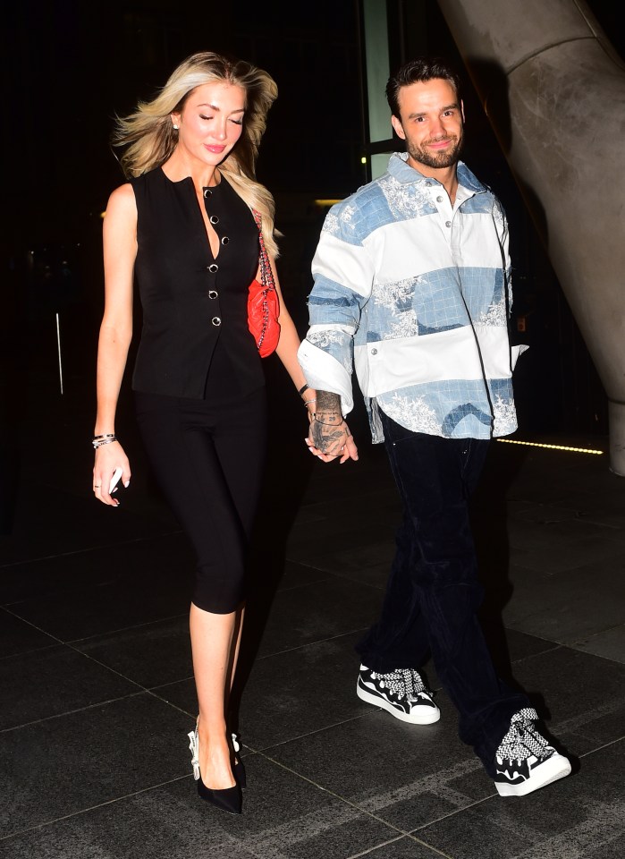 a man and a woman hold hands while walking down the street