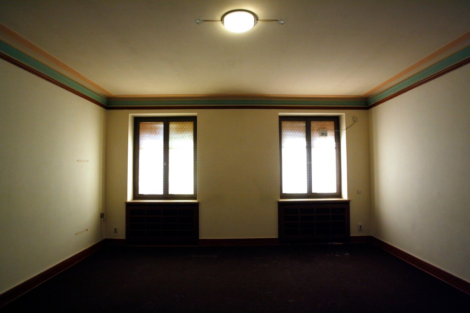 an empty room with two windows and a light on the ceiling