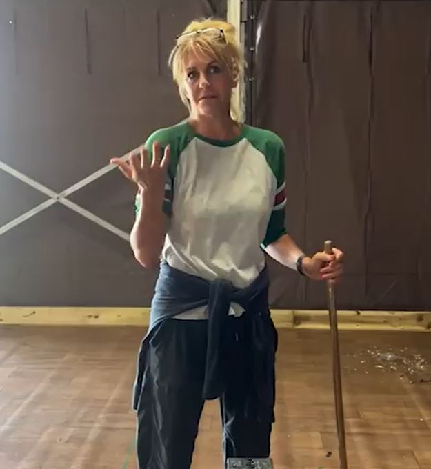 a woman is standing on a wooden floor holding a mop .