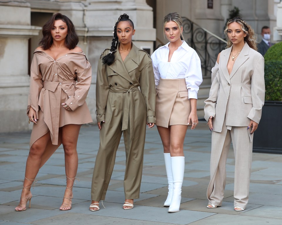 four women are standing next to each other on a sidewalk