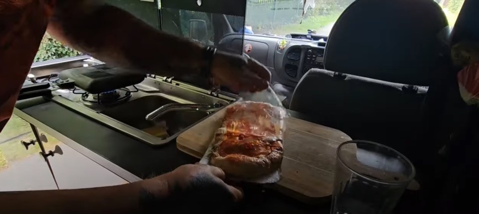 He makes himself a pizza using his tiny stove in the van