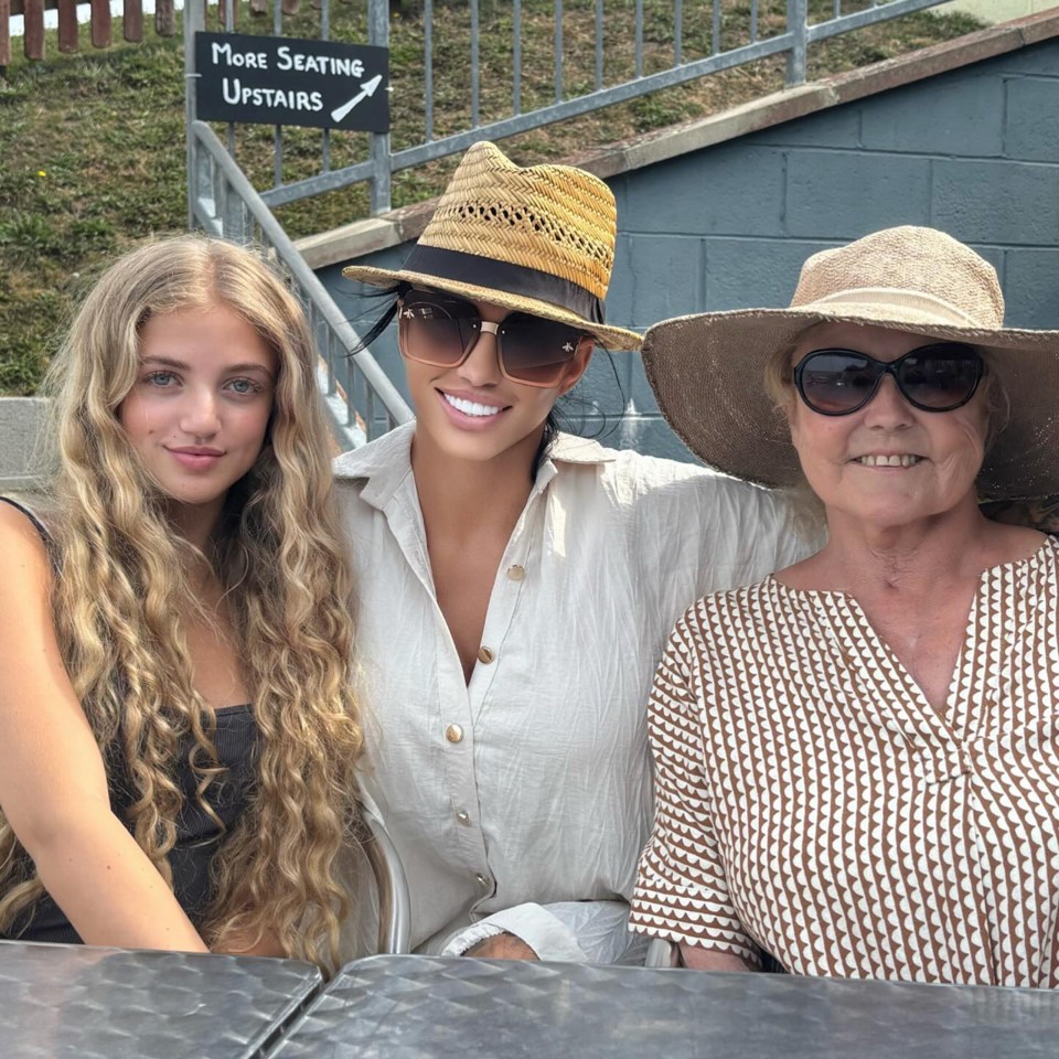 three women pose in front of a sign that says more seating upstairs