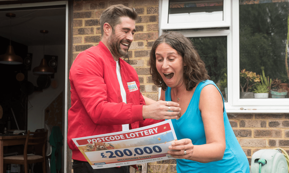 a man is giving a woman a postcode lottery ticket