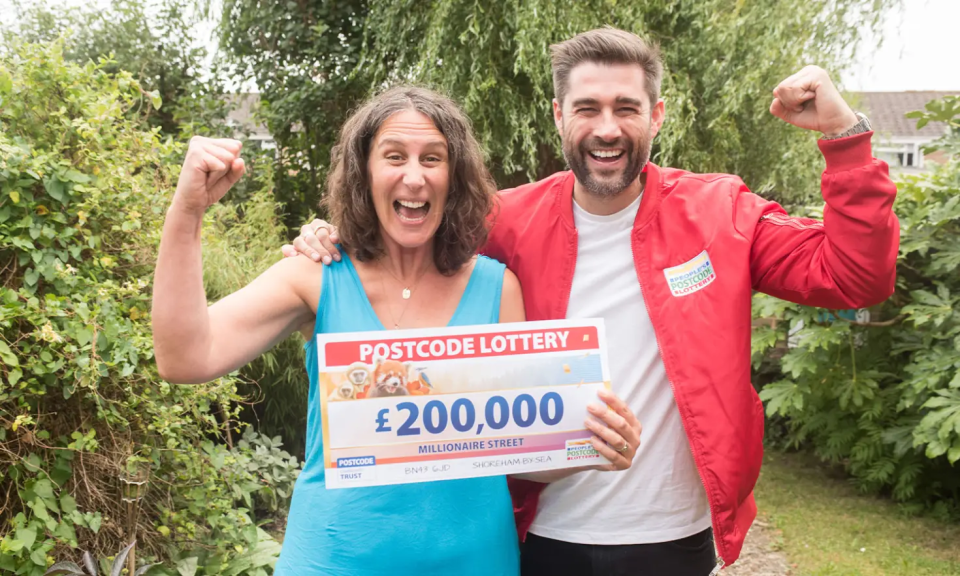 a man and woman holding a postcode lottery ticket