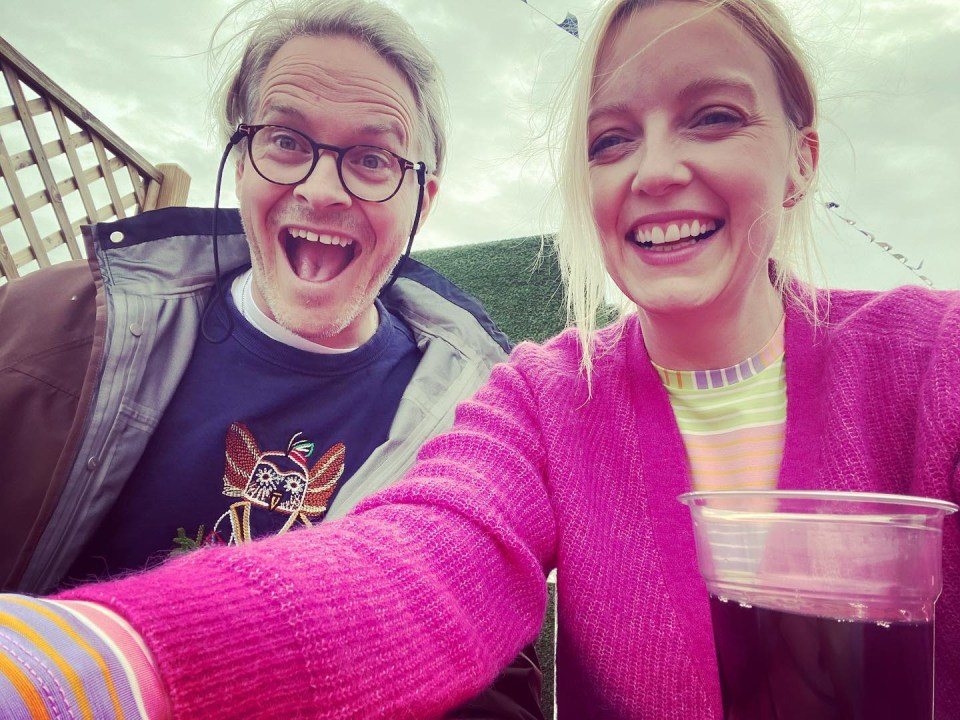 a man and a woman are posing for a picture and the woman is wearing a pink sweater